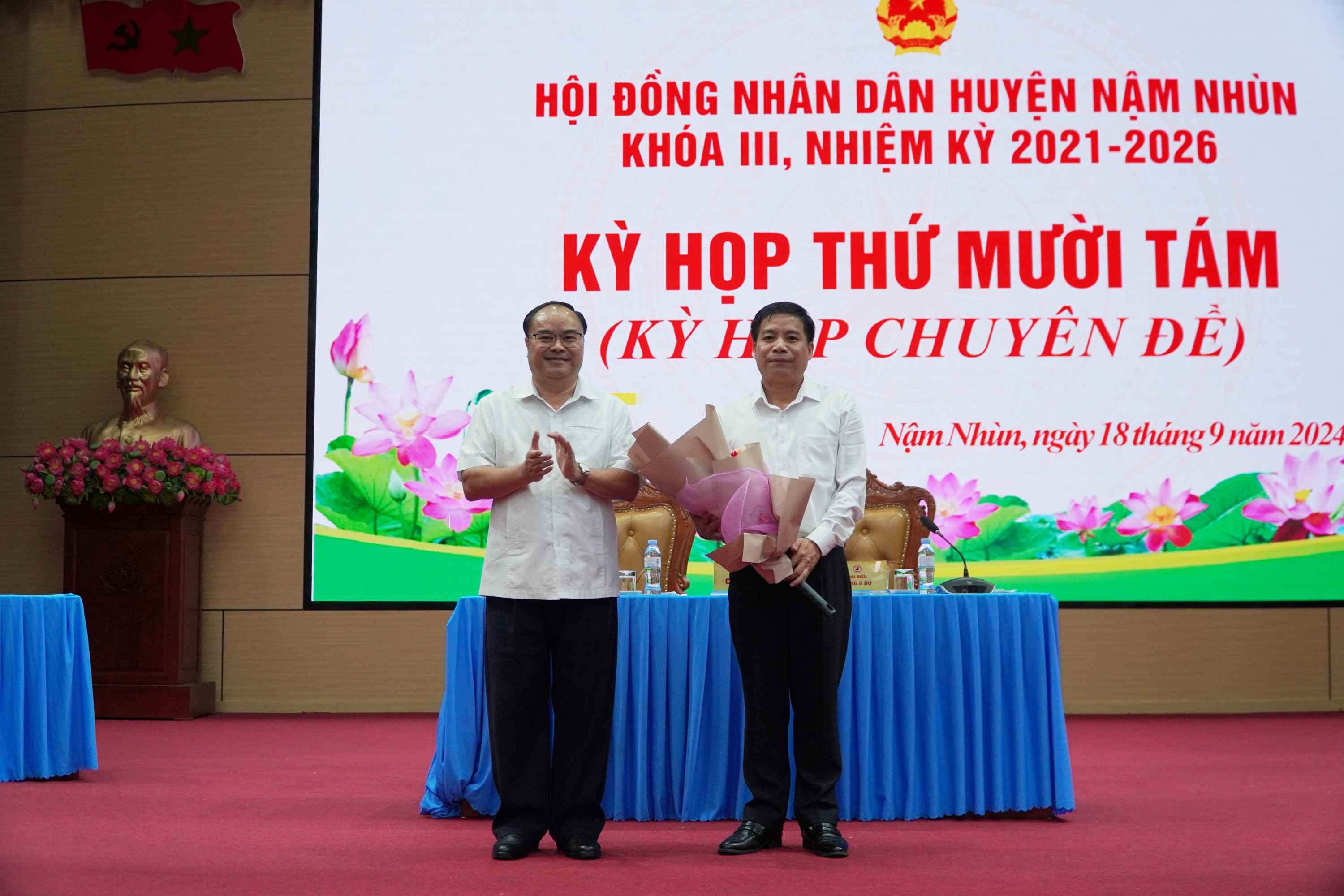 Đồng chí Mùa A Trừ - Tỉnh ủy viên, Bí thư Huyện ủy Nậm Nhùn tặng hoa chúc mừng đồng chí Nguyễn Văn Ninh.