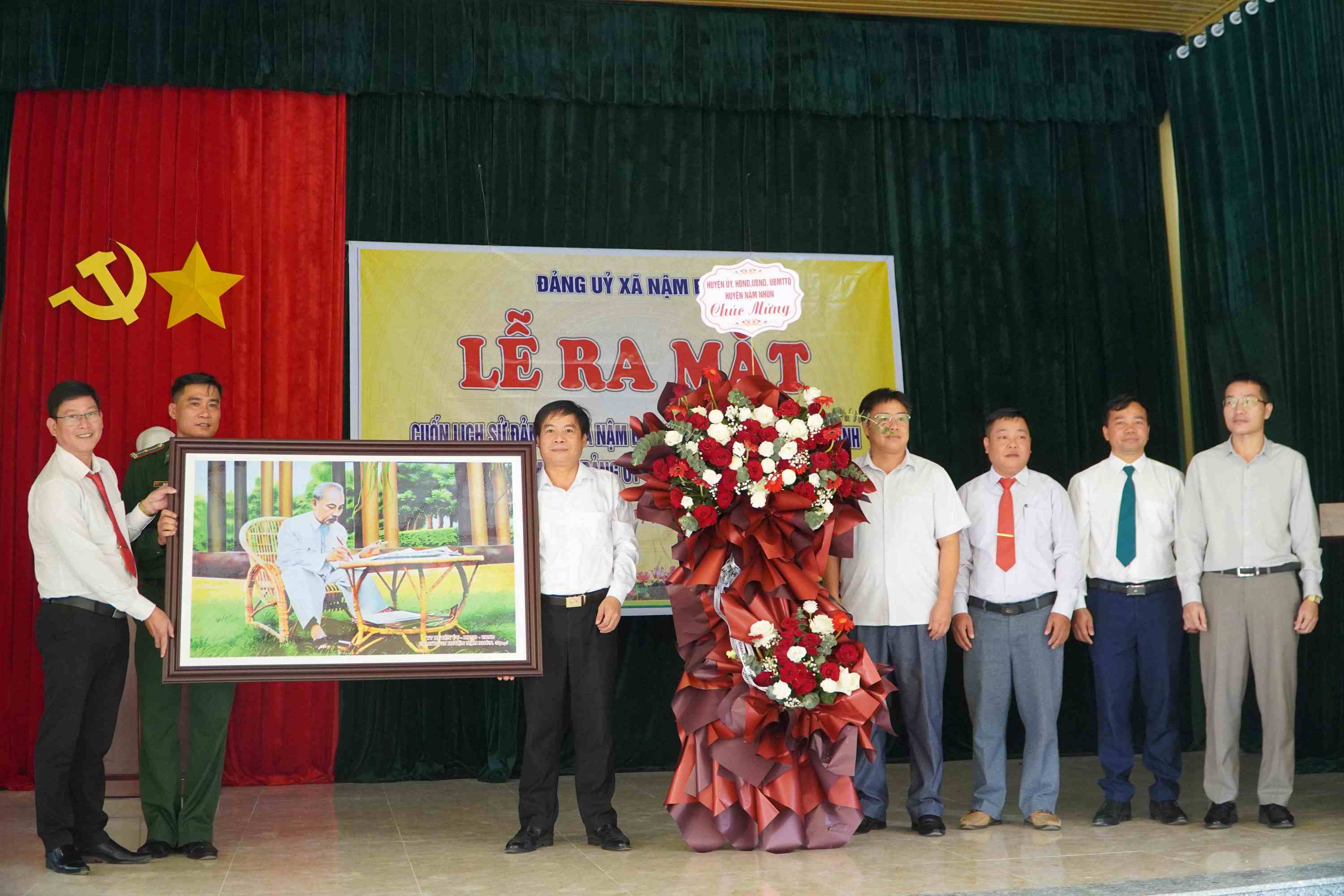 Lãnh đạo UBND huyện Nậm Nhùn tặng tranh và hoa chúc mừng lễ ra mắt cuốn lịch sử Đảng bộ và khánh thành trụ sở làm việc xã.