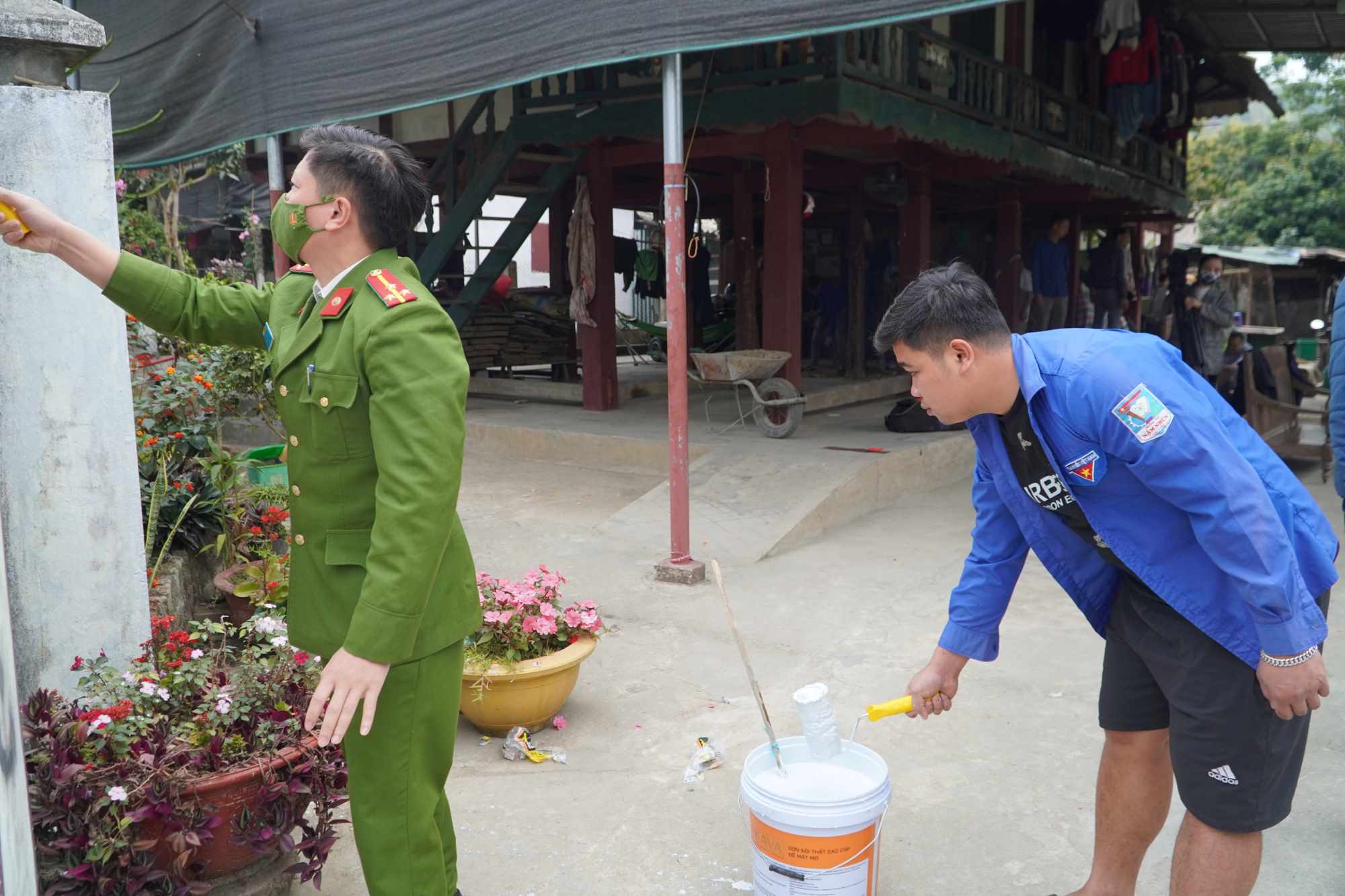 Cán bộ, công chức, lực lượng dân quân tự vệ và Công an thị trấn Nậm Nhùn sơn sửa lại hàng rào cho gia đình được hỗ trợ.